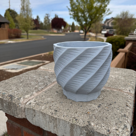 Sky Blue textured cement pot on a stone ledge with a suburban street in the background